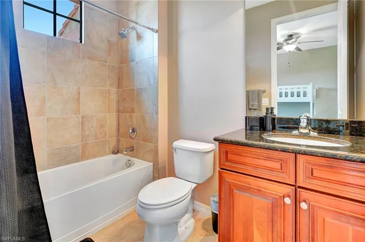 Full bath featuring shower / bath combination with curtain, vanity, ceiling fan, and tile patterned flooring