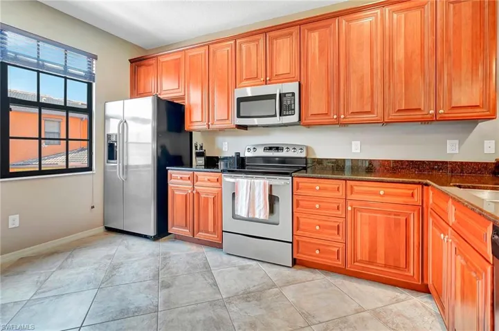 Kitchen featuring stainless steel appliances, brown cabinets, and dark stone counters