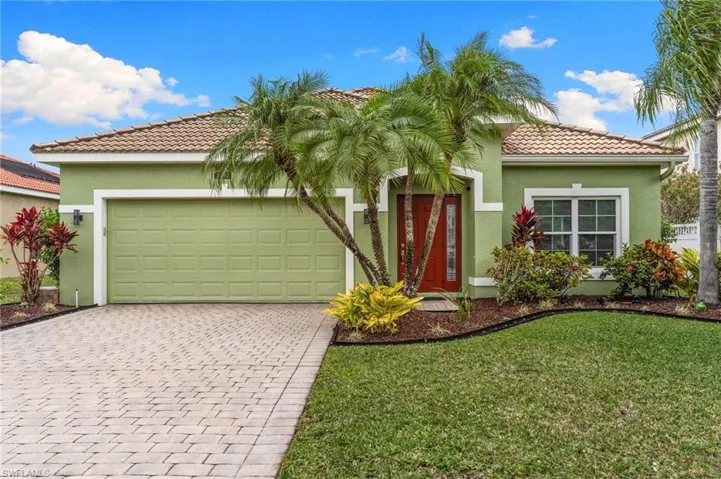 Mediterranean / spanish-style home with stucco siding, a front yard, a tiled roof, and driveway