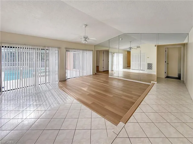 Unfurnished living room with light tile patterned flooring, lofted ceiling, a textured ceiling, and ceiling fan