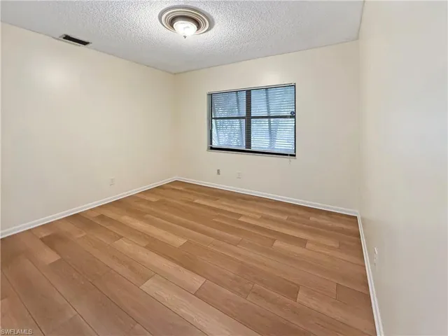 Unfurnished room featuring light wood-type flooring and a textured ceiling
