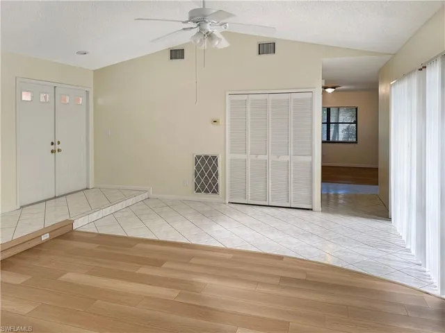 Foyer entrance featuring wood finished floors, a textured ceiling, ceiling fan, and lofted ceiling