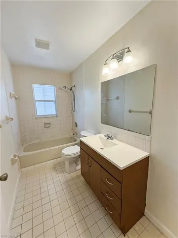 Full bath with bathing tub / shower combination, vanity, and light tile patterned flooring