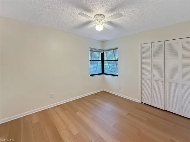 Unfurnished bedroom featuring light wood-style floors, a textured ceiling, a ceiling fan, and a closet