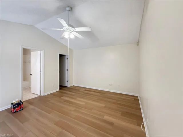Unfurnished bedroom featuring light wood-style flooring, lofted ceiling, a textured ceiling, a ceiling fan, and ensuite bath