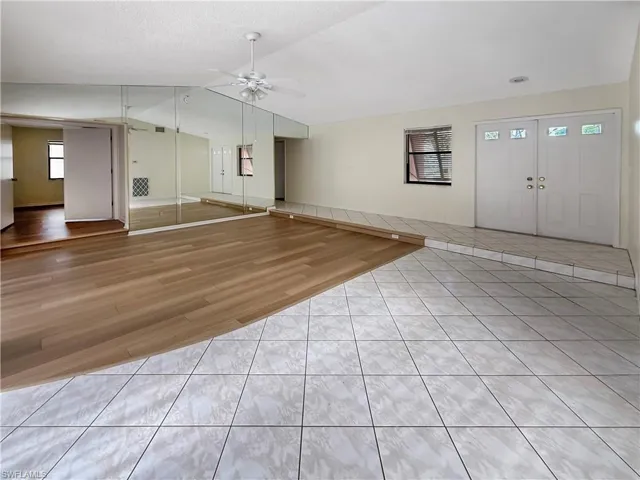 Entryway featuring light tile patterned flooring, lofted ceiling, ceiling fan, and a textured ceiling