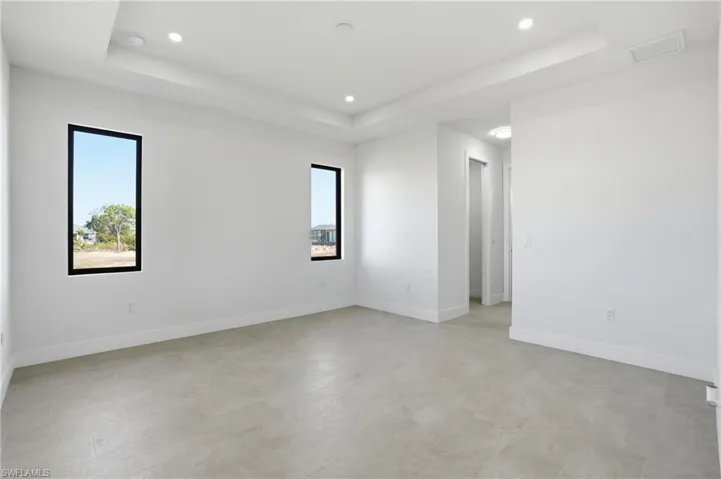 Master bedroom with a raised ceiling and recessed lighting