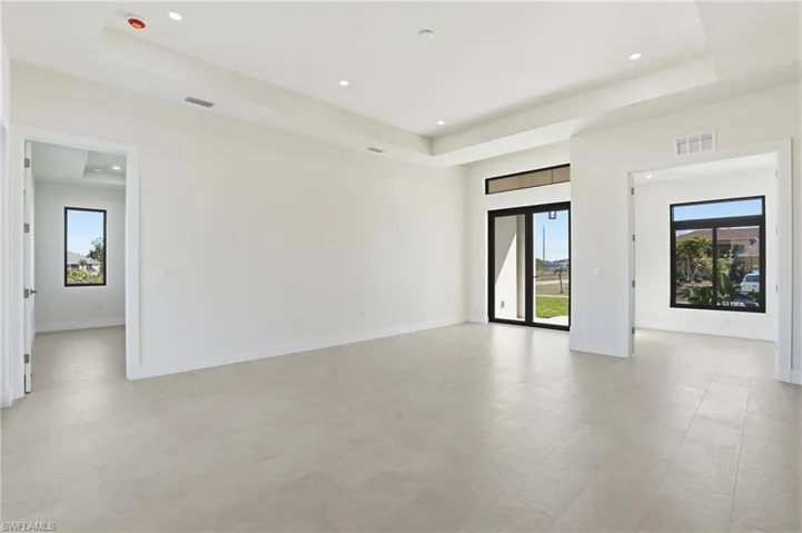 Empty room with a raised ceiling, plenty of natural light, and recessed lighting