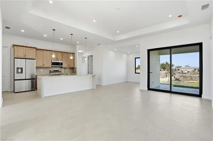 Unfurnished living room with a raised ceiling and baseboards