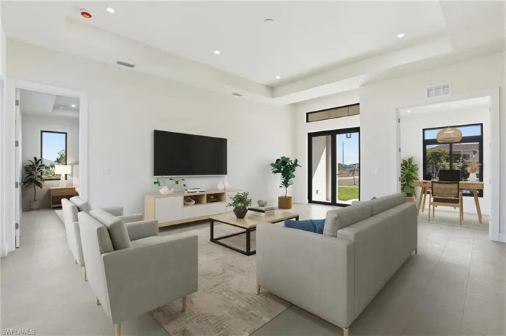 Living room with recessed lighting, a desk, and a high tray ceiling