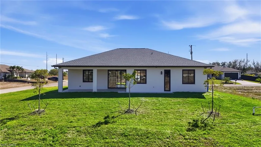 View of front facade featuring roof with shingles, a patio area, a front yard, and stucco siding