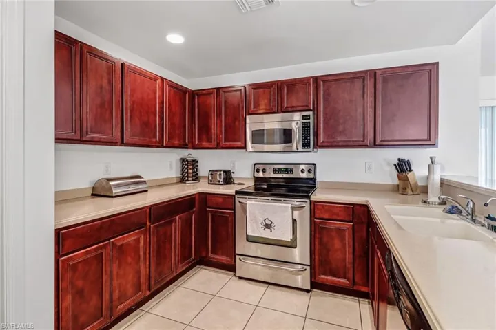 Kitchen with sink, light tile patterned floors, and appliances with stainless steel finishes