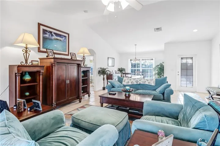 Living room featuring lofted ceiling, ceiling fan, and light tile patterned floors