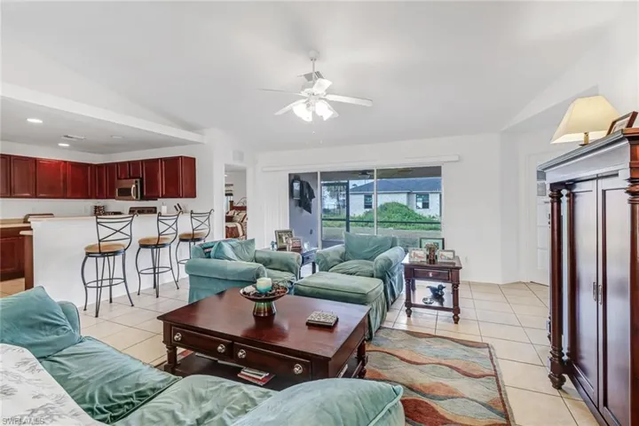 Tiled living room featuring lofted ceiling and ceiling fan