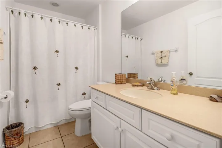 Bathroom with tile patterned floors, a shower with curtain, toilet, and vanity