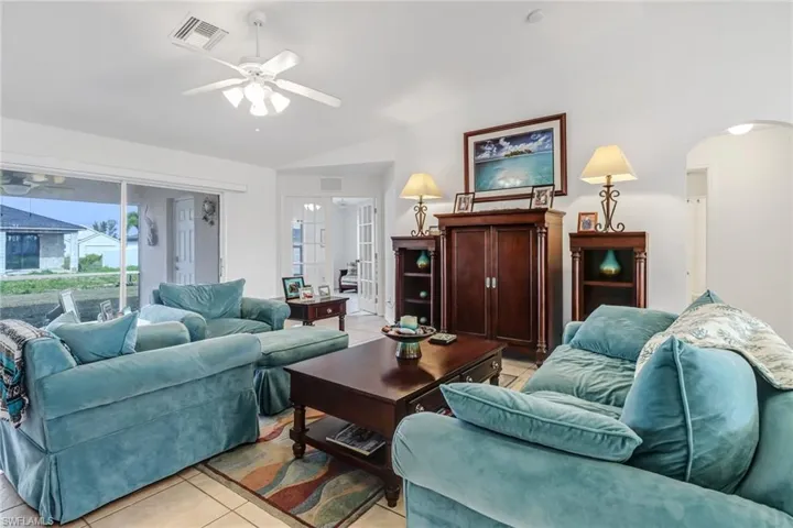 Living room featuring lofted ceiling, ceiling fan, and light tile patterned floors