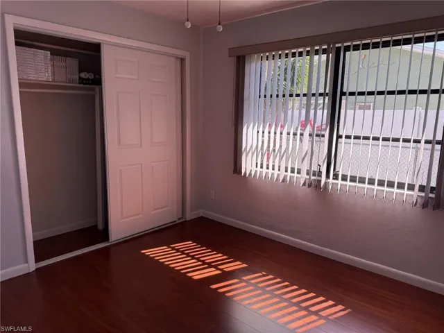 Unfurnished bedroom featuring a closet and dark wood-style flooring