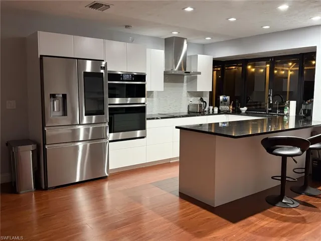 Kitchen with a peninsula, stainless steel appliances, a kitchen bar, modern cabinets, and decorative backsplash