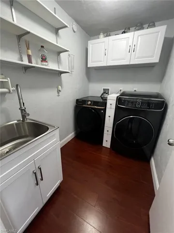 Laundry area with cabinet space, dark wood finished floors, and washer and clothes dryer
