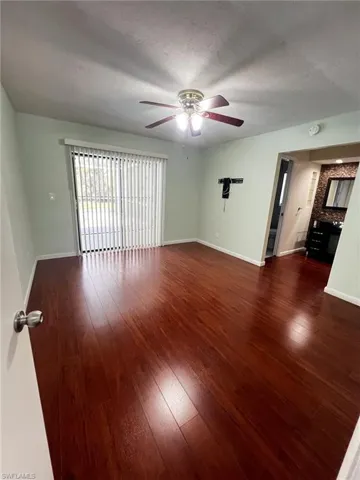 Empty room featuring dark wood finished floors, a ceiling fan, and a textured ceiling