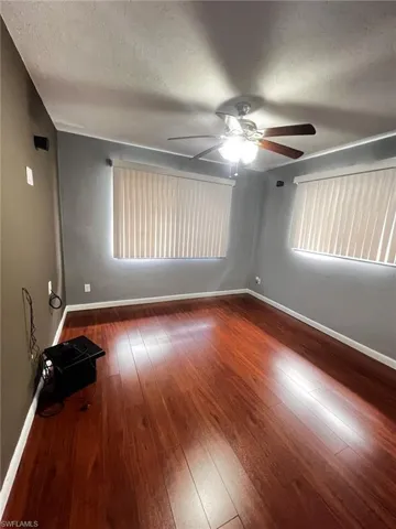 Unfurnished room featuring a textured ceiling, ceiling fan, and dark wood-style floors