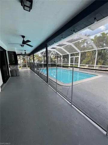 Outdoor pool with a sunroom, glass enclosure, and a patio
