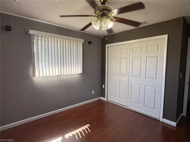 Unfurnished bedroom with dark wood-style flooring, a ceiling fan, a closet, and a textured ceiling