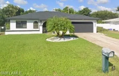 View of front facade featuring a front lawn, driveway, and an attached garage