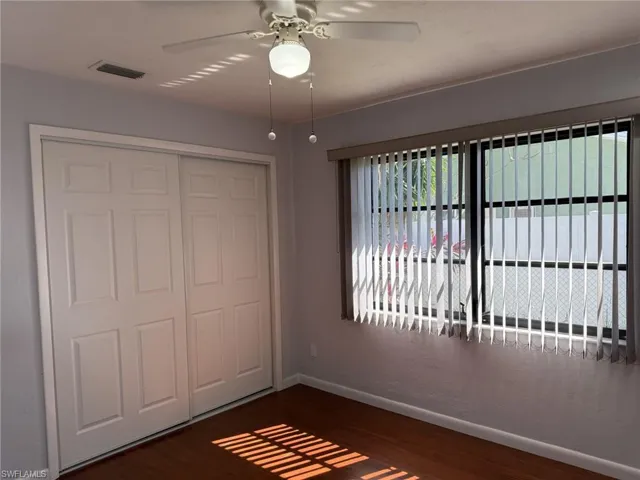 Unfurnished bedroom with a closet, dark wood-style flooring, and ceiling fan