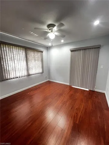 Spare room featuring dark wood-style flooring and a ceiling fan