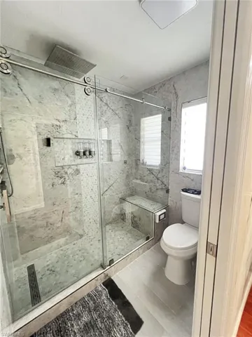Bathroom featuring toilet and a marble finish shower
