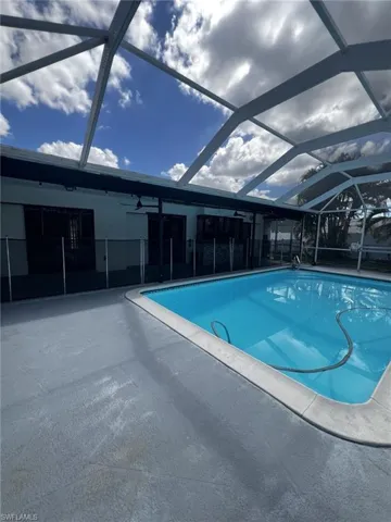 Outdoor pool featuring glass enclosure, a sunroom, and a patio