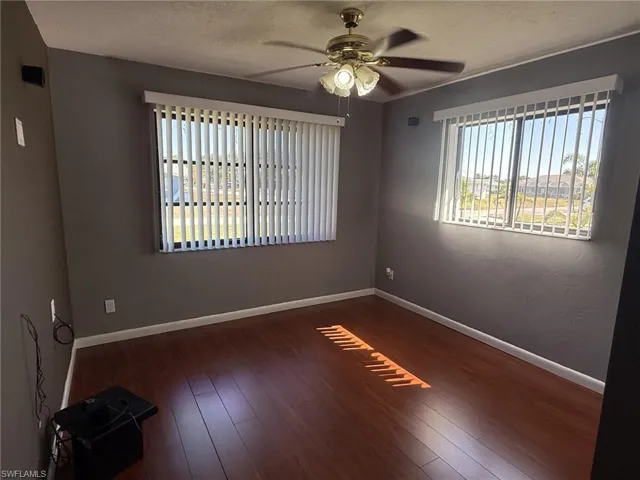 Empty room with a ceiling fan, dark wood-style flooring, and a textured ceiling