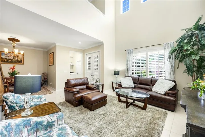 Living area with light tile patterned floors, crown molding, and a chandelier