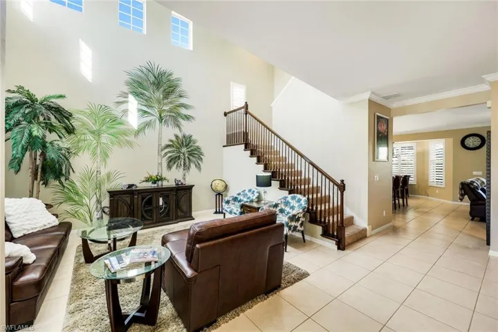 Living room featuring stairway, light tile patterned floors, and crown molding