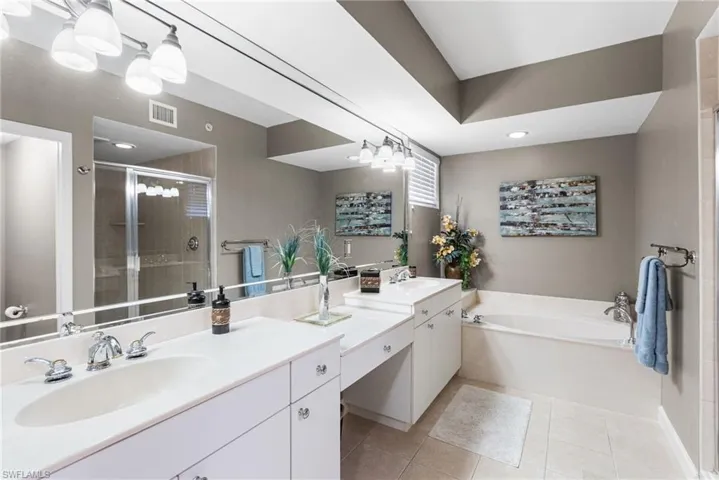 The primary spa-inspired bathroom is beautifully appointed with a separate walk-in shower and a tranquil soaking tub, creating a serene, resort-like retreat. Tray ceilings add architectural elegance and height, enhancing the sense of openness and luxury throughout this private sanctuary.