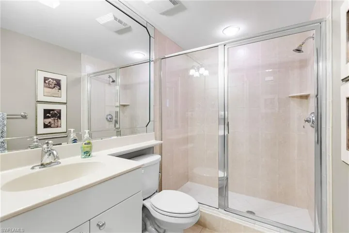 The third full bathroom is elegantly appointed with a walk-in shower finished in floor-to-ceiling porcelain tile and a sleek single vanity, offering a refined and modern aesthetic. Conveniently located just outside the den/third bedroom, it also serves as a sophisticated guest bath, providing both comfort and privacy for visiting guests.