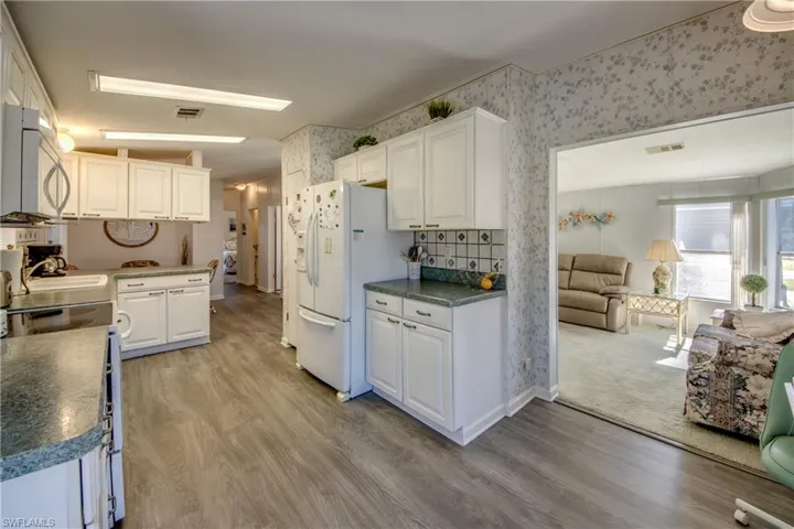Kitchen featuring sink, white cabinets, white appliances, and light wood-type flooring