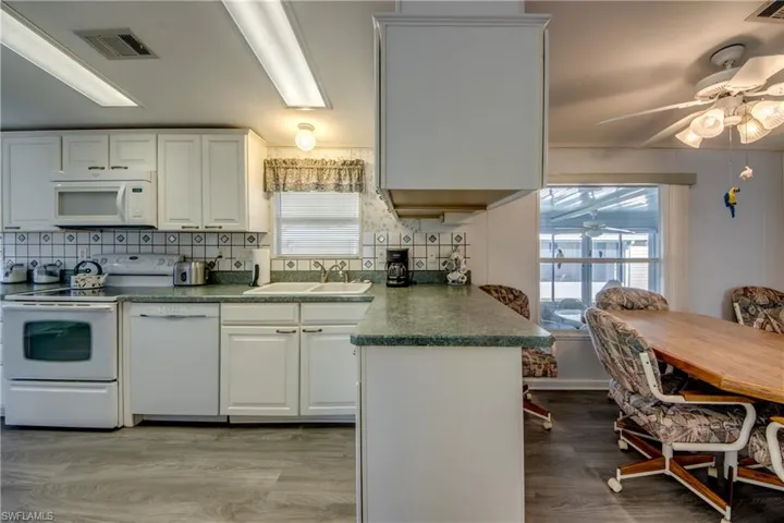 Kitchen featuring white cabinets, white appliances, a wealth of natural light, and sink
