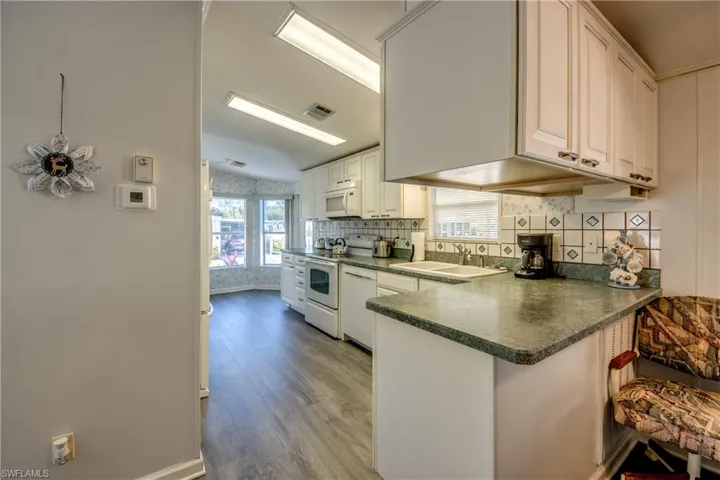 Kitchen featuring kitchen peninsula, sink, white cabinets, and plenty of natural light