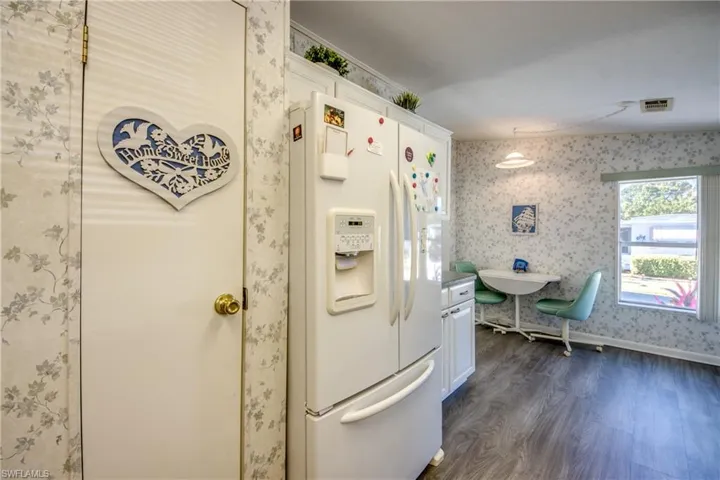 Kitchen featuring dark hardwood / wood-style flooring, white fridge with ice dispenser, and white cabinets