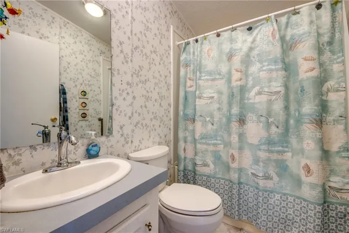 Full bathroom featuring a textured ceiling, vanity, toilet, and shower / tub combo with curtain