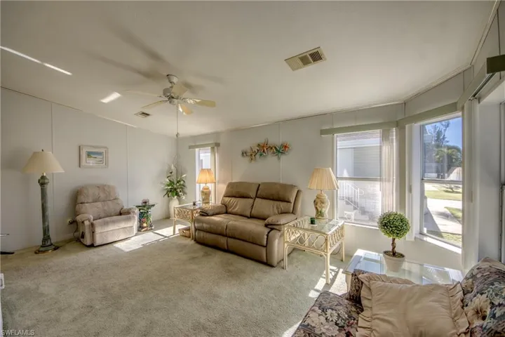 Carpeted living room featuring a wealth of natural light and ceiling fan