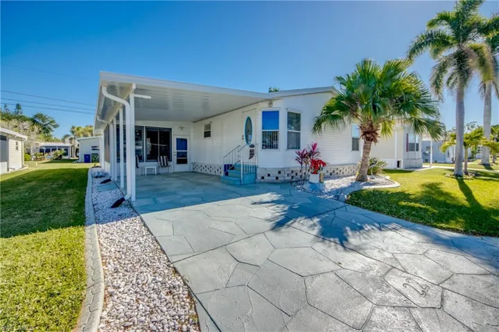 Rear view of property with a carport and a lawn