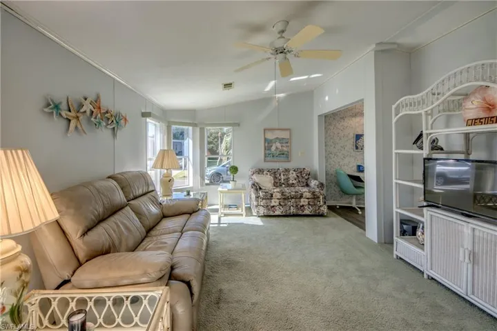 Living room with carpet, ceiling fan, lofted ceiling, and ornamental molding