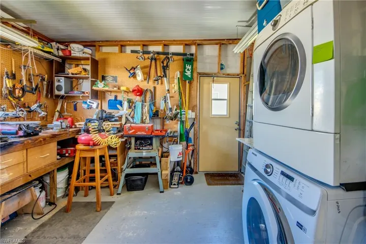 Washroom with a workshop area and stacked washer / drying machine