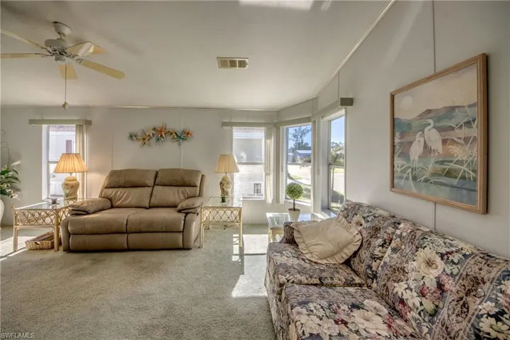 Living room with ceiling fan, carpet floors, and crown molding