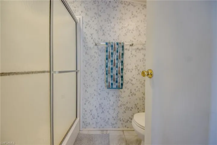 Bathroom with tile patterned floors, toilet, and a shower with shower door