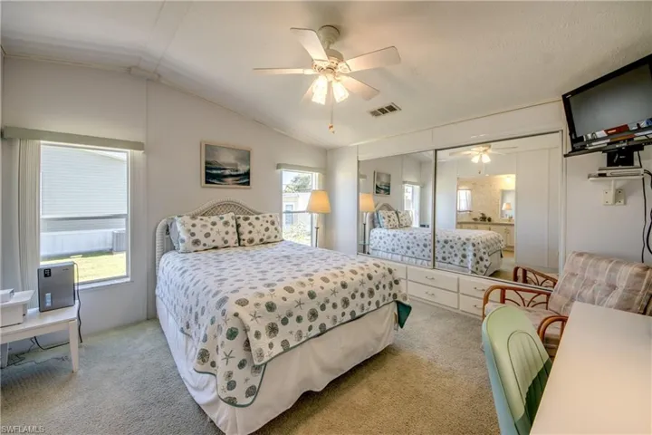 Bedroom featuring a closet, vaulted ceiling, ceiling fan, and light colored carpet