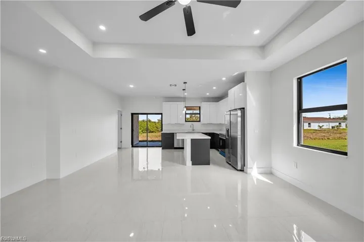 Kitchen featuring open floor plan, a kitchen island, a tray ceiling, white cabinets, and recessed lighting